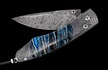 William Henry Knife
Knife Frame Type: 'Mind Melt' damascus
Frame Engraver: Chad Nichols
Blade Type: 'Hornet's Nest' damascus
Damascus Artisan: Mike Norris
Scale/Inlay: 0,000 year-old fossil Woolly Mammoth tooth
Number: 065/100
Gemstones/Embellishme